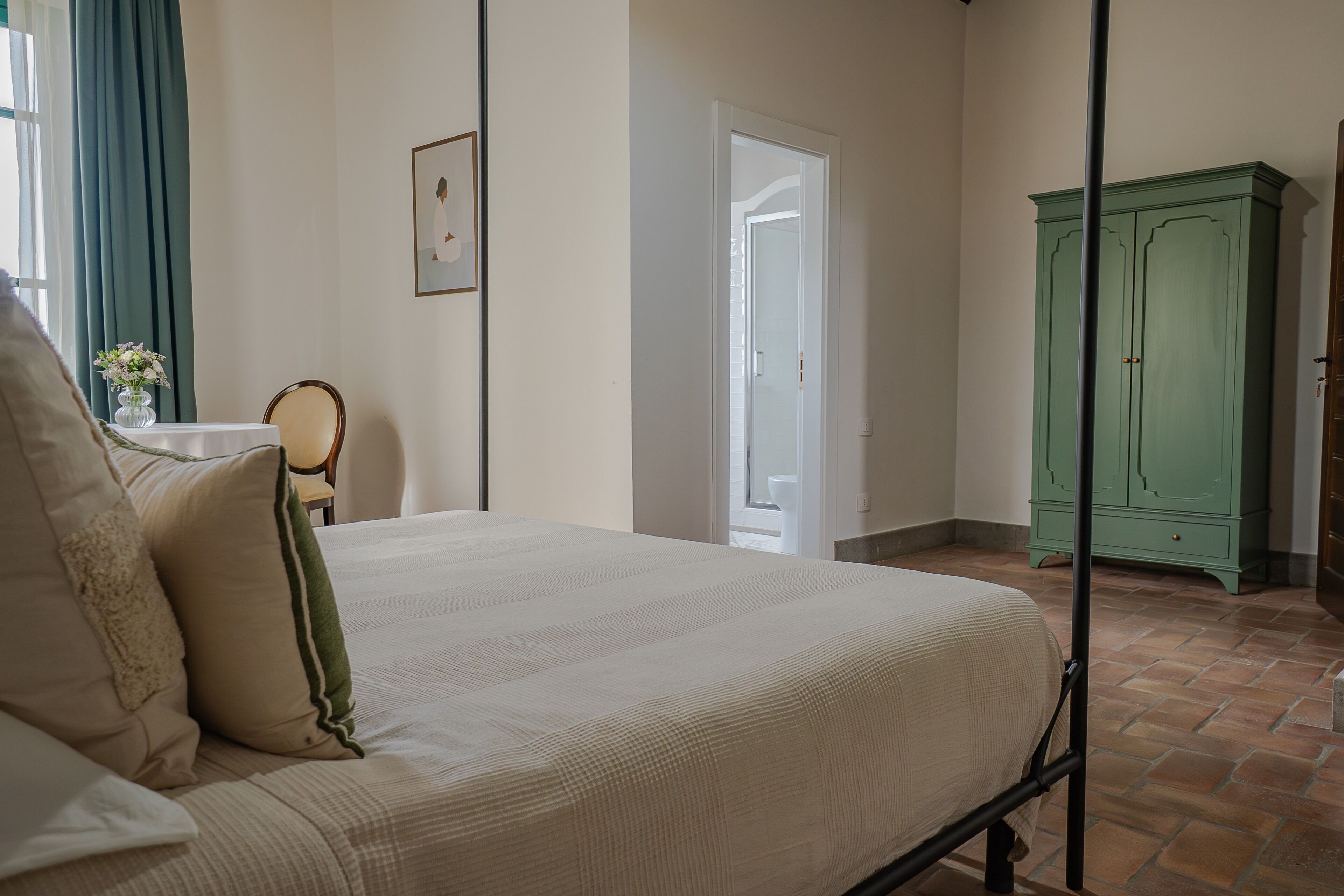 Et soveværelse med en seng, et natbord, en grøn garderobe og en dør til et andet rum.