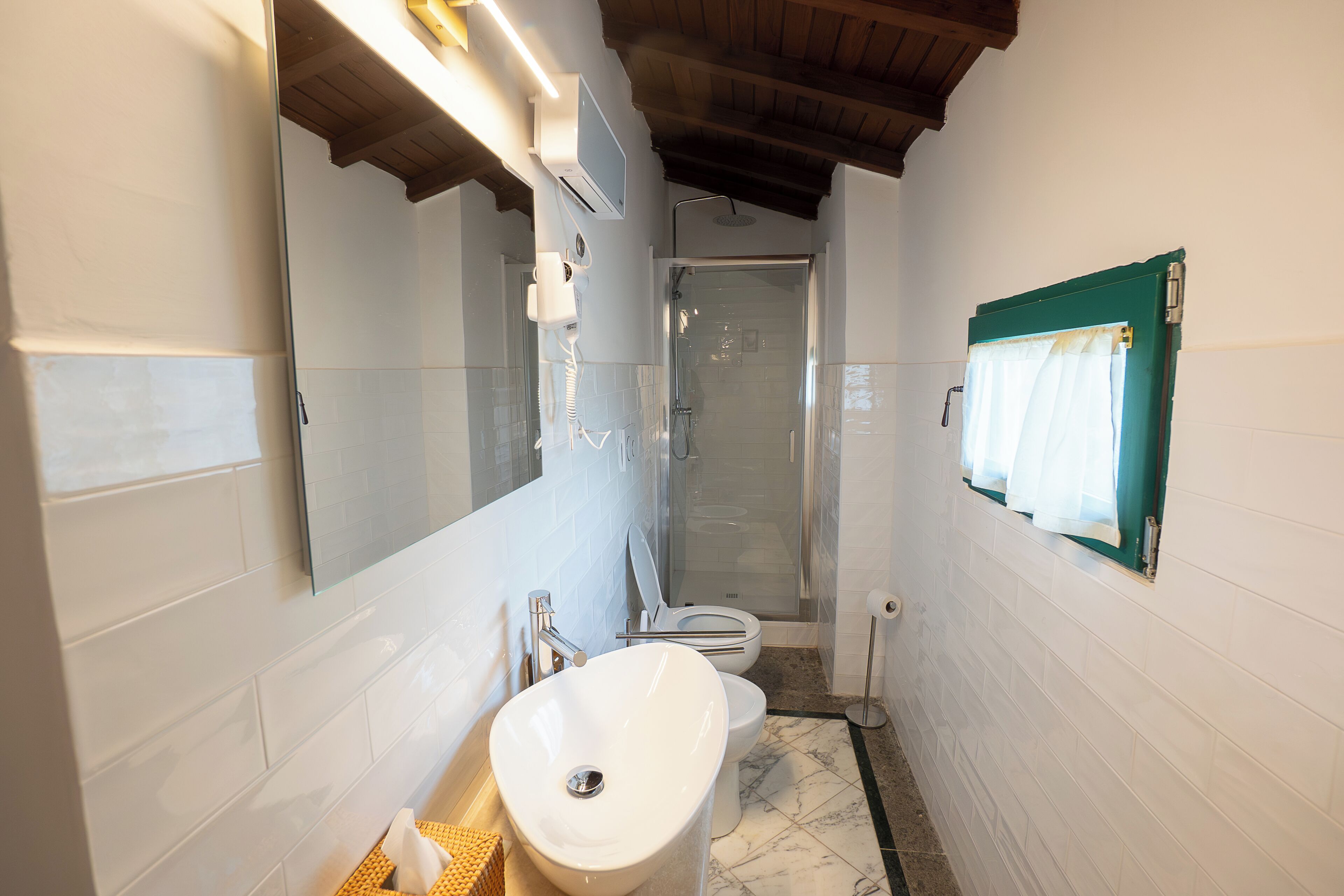 Une petite salle de bain avec un lavabo blanc, une cabine de douche en verre et un miroir.