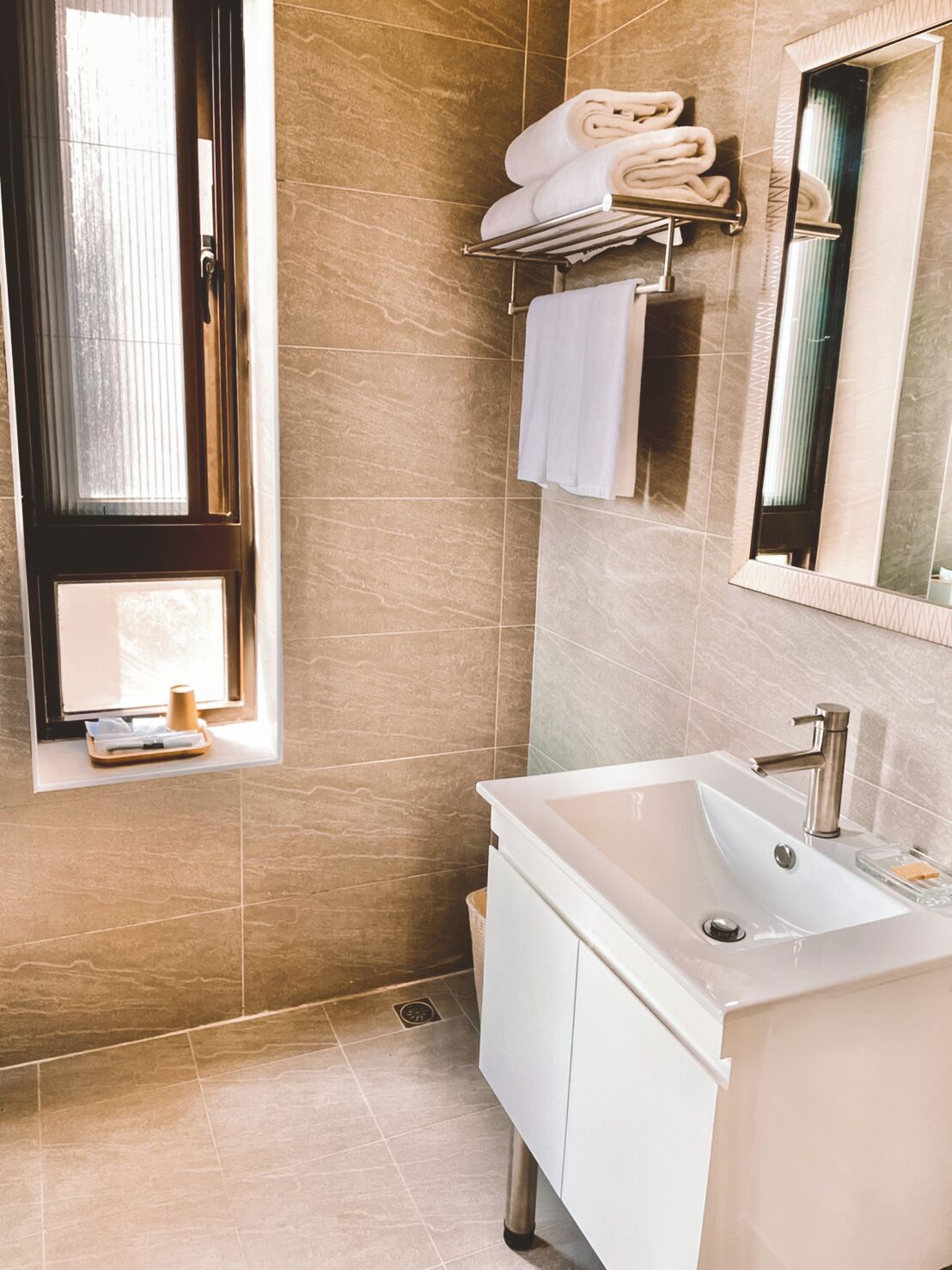 A modern bathroom with a large sink, a mirror, and a towel rack.