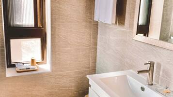 A modern bathroom with a large sink, a mirror, and a towel rack.