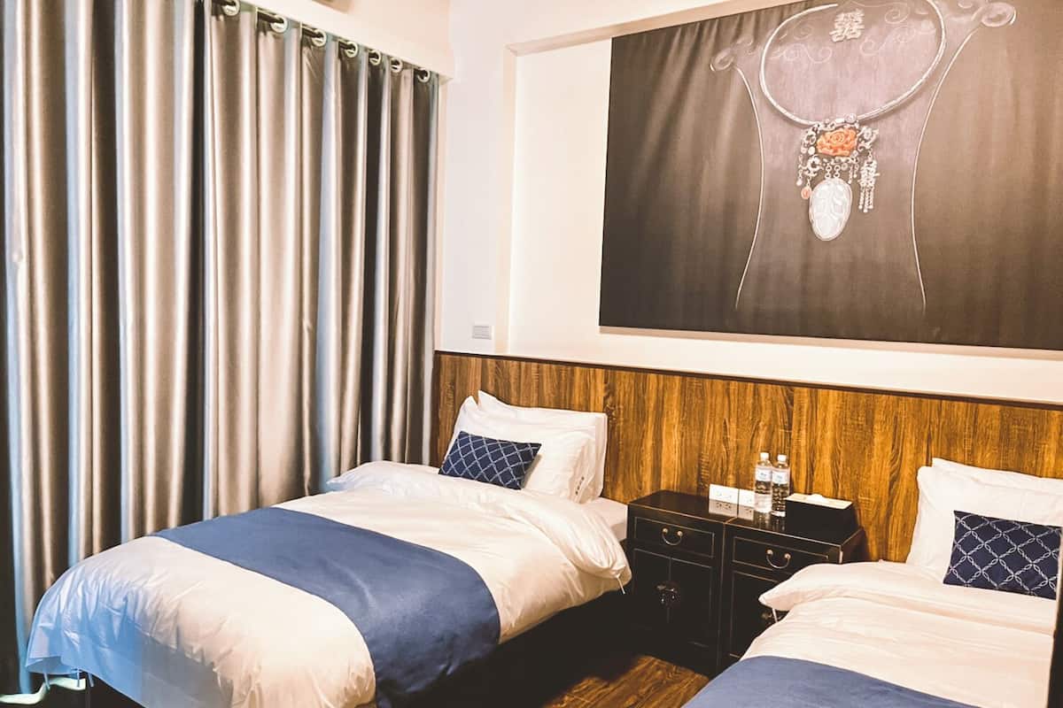 Habitación de hotel con dos camas, cabecera de madera, mesita de noche y un cuadro grande en la pared.