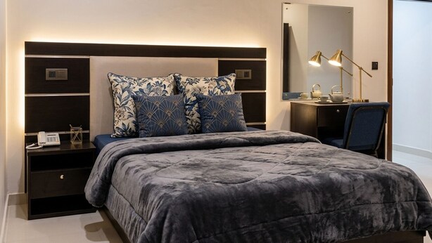 A bedroom with a bed, bedside tables, a desk, and a mirror.