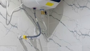 A water heater mounted on a wall with marble tiles.