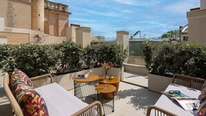 Terraço no telhado com área de estar ao ar livre, vista da cidade e um edifício de tijolos ao fundo.
