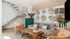Uma sala de estar moderna com escada, sofás e pratos decorativos na parede.