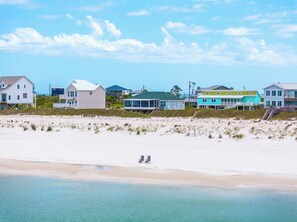 A beachside property with a sandy beach, a few beach chairs, and a small structure in the water. - ☀️ Short Walk to Beach - Pet Friendly - Turtles Nest 🌴 (Cape San Blas)