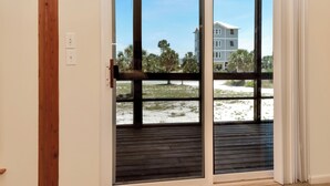 Una habitación con puerta corrediza de vidrio que da a un espacio exterior con vista a un edificio y árboles.