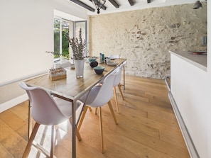 A dining area with a wooden table, white chairs, a vase with plants, and a stone wall. - House with garden, 4 adults 1 child (Pleurtuit)
