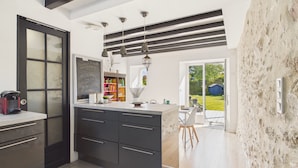 Cozinha moderna com armários escuros, uma lousa e vista para o pátio externo.