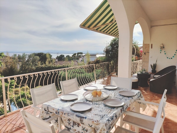 A terrace with a table set for dining, overlooking a scenic landscape. - BOUGANVILLA HOUSE SEA VIEW (Roses)