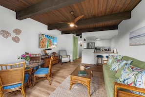 Ein geräumiger Wohnbereich mit Esstisch, Stühlen, einer Couch und einer Küche im Hintergrund.