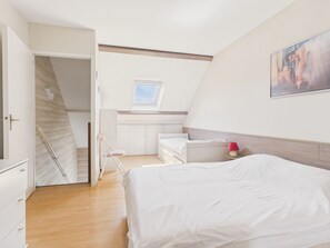 Ein Schlafzimmer mit Bett, Schreibtisch, Stuhl, Fenster und Treppe.