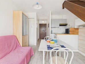 A compact living space with a kitchenette, a dining area, and a small seating area with a pink blanket. - Apartment for 2 - 800 from beach - shared pool (Le Pouliguen)
