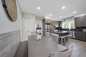 A modern kitchen with a central island, stainless steel appliances, and a dining area with a bench and chairs.