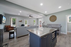 A spacious living area with a large island, a sofa, and a dining table.