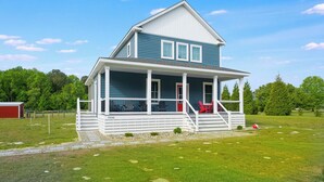 Ein zweistöckiges Haus mit Veranda, einer roten Tür und der Hausnummer 33600 an der Seite.