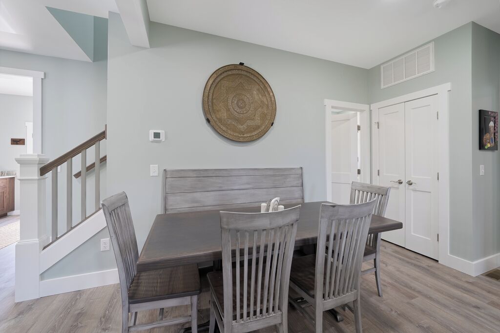 Un comedor con una mesa y sillas de madera, un plato decorativo en la pared y una puerta blanca.