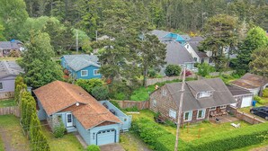 Ett bostadsområde med hus, en uppfart och en skogbeklädd kulle i bakgrunden.