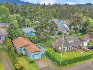 A residential area with houses, a driveway, and a forested hill in the background.