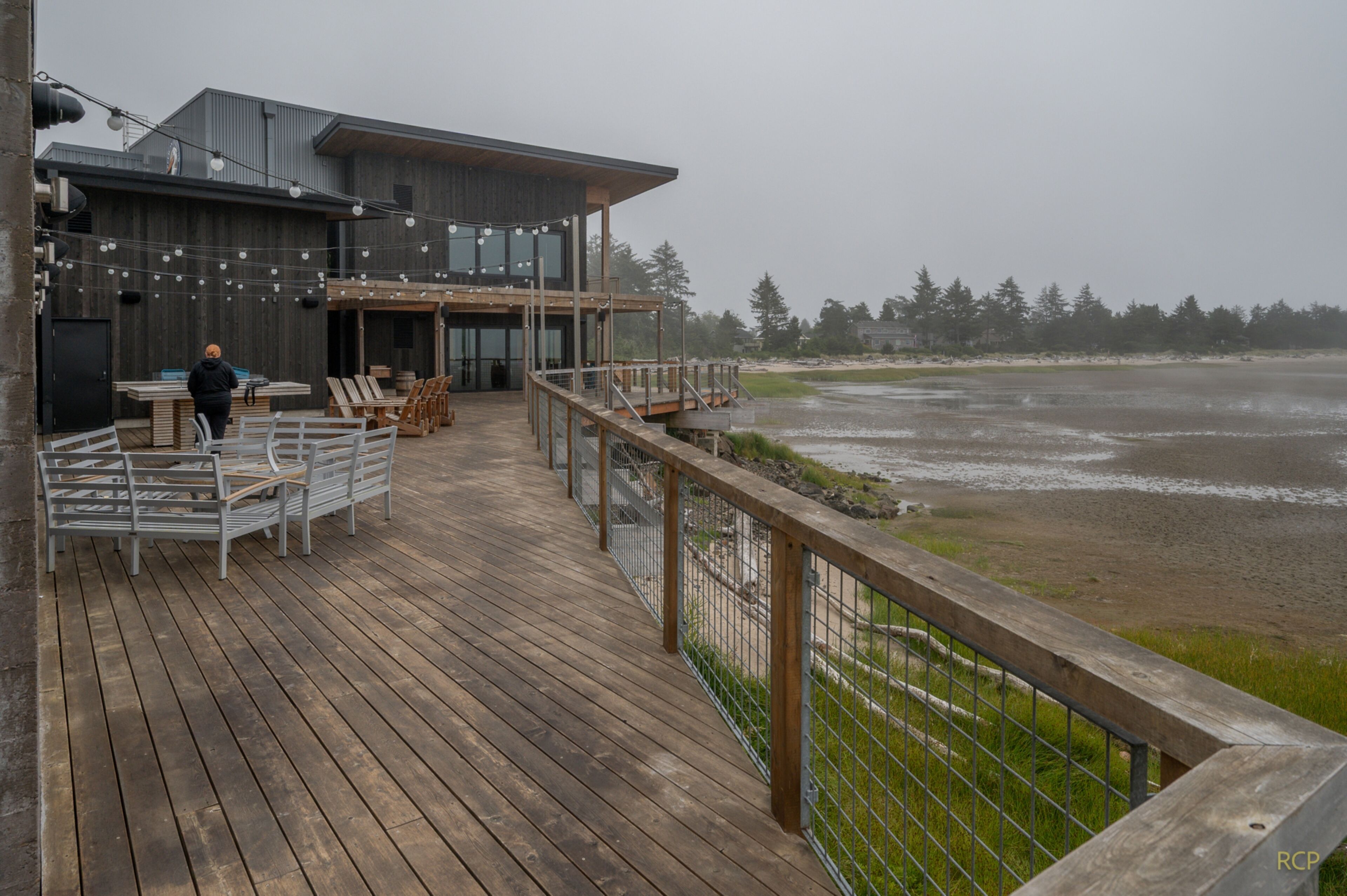 A wooden deck with outdoor seating and a view of the beach.