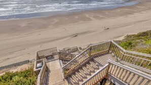 Eine Holztreppe führt zu einem Sandstrand mit Blick auf den Ozean.