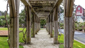 Ein überdachter Gang mit Holzsäulen und einem Kiesweg.
