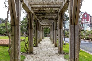 Ein überdachter Gang mit Holzsäulen und einem Kiesweg.