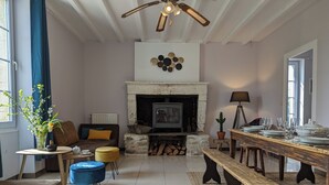 A living room with a fireplace, a sofa, a coffee table, and a dining table set for six. - The Chestnut (Chadurie)