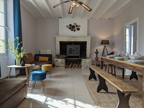 A living room with a fireplace, a sofa, a coffee table, and a dining table set for six. - The Chestnut (Chadurie)