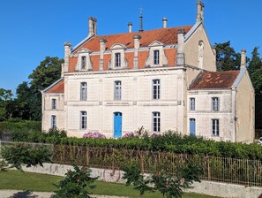 A large, historic building with multiple windows and a prominent blue door, surrounded by lush greenery and a fence. - The Chestnut (Chadurie)
