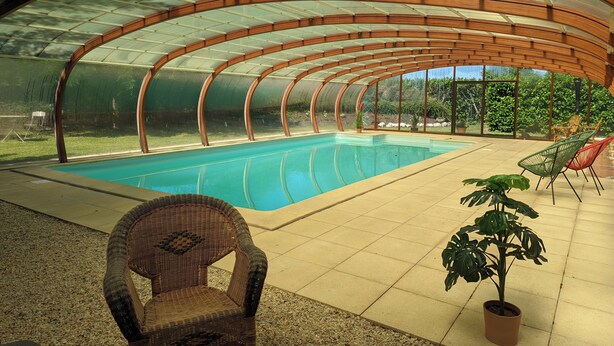 An indoor swimming pool with a curved roof, surrounded by seating and potted plants. - The Chestnut (Chadurie)