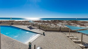 Una piscina con sillas de descanso y vistas a la playa.