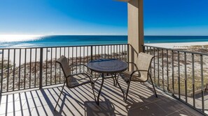 Varanda com mesa e cadeiras com vista para a praia.