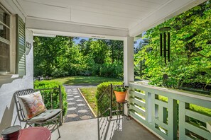 Une véranda abritée avec une chaise, une table et un pot de fleurs.