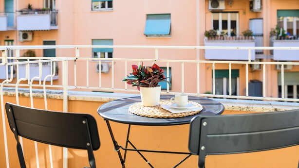 A balcony with a table, chairs, a potted plant, and a cup. - Vatican Area Apartment with 2 Bedrooms and 2 Baths (Roma)