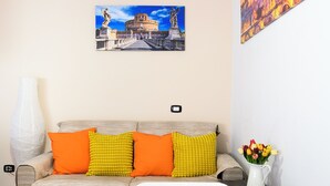 A room with a sofa, a table with lemons, a vase with flowers, and two paintings on the wall. - Vatican Area Apartment with 2 Bedrooms and 2 Baths (Roma)