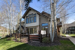 A two-story house with a large front porch, a wooden fence, and a stone foundation. - Deer Valley Townhome Walkable Location + Hot Tub 3 Bedroom Condo (Park City)