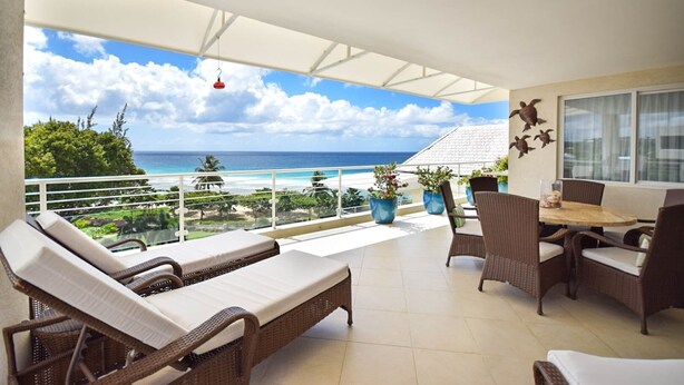 A balcony with wicker furniture, potted plants, and a view of the ocean. - Palm Beach 610 2 Bedroom Apts (Hastings)