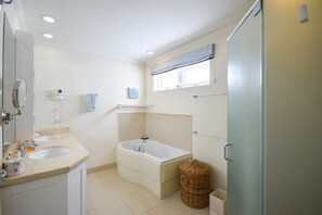 A bathroom with two sinks, a bathtub, a window, and a shower. - Palm Beach 610 2 Bedroom Apts (Hastings)