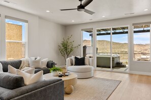 Ein modernes Wohnzimmer mit grauem Sofa, einem runden Couchtisch und einem weißen Sessel.