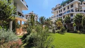 A modern apartment complex with multiple balconies, lush greenery, and a well-maintained lawn. - ALLONBAY beach front residence (Villajoyosa)