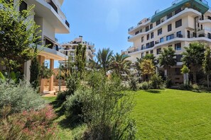 A modern apartment complex with multiple balconies, lush greenery, and a well-maintained lawn. - ALLONBAY beach front residence (Villajoyosa)