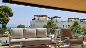 A modern outdoor seating area with a sofa and chairs, a table, and a view of a coastal building complex. - ALLONBAY beach front residence (Villajoyosa)