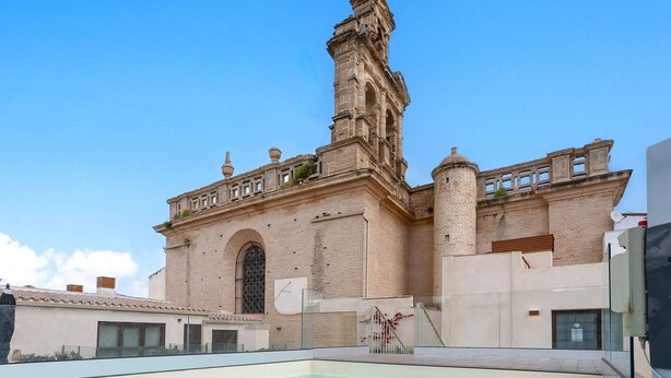 A historic building with a prominent tower, a swimming pool, and a clear blue sky. - Exclusive Duplex With Private Terrace Pool in Seville Feria 21 (Seville)