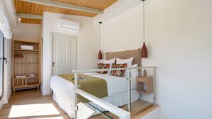 A bedroom with a bed, bedside table, hanging light, wardrobe, and an air conditioning unit. - Exclusive Duplex With Private Terrace Pool in Seville Feria 21 (Seville)