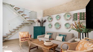 A modern living room with a staircase, a sofa, chairs, a coffee table, and decorative plates on the wall. - Exclusive Duplex With Private Terrace Pool in Seville Feria 21 (Seville)