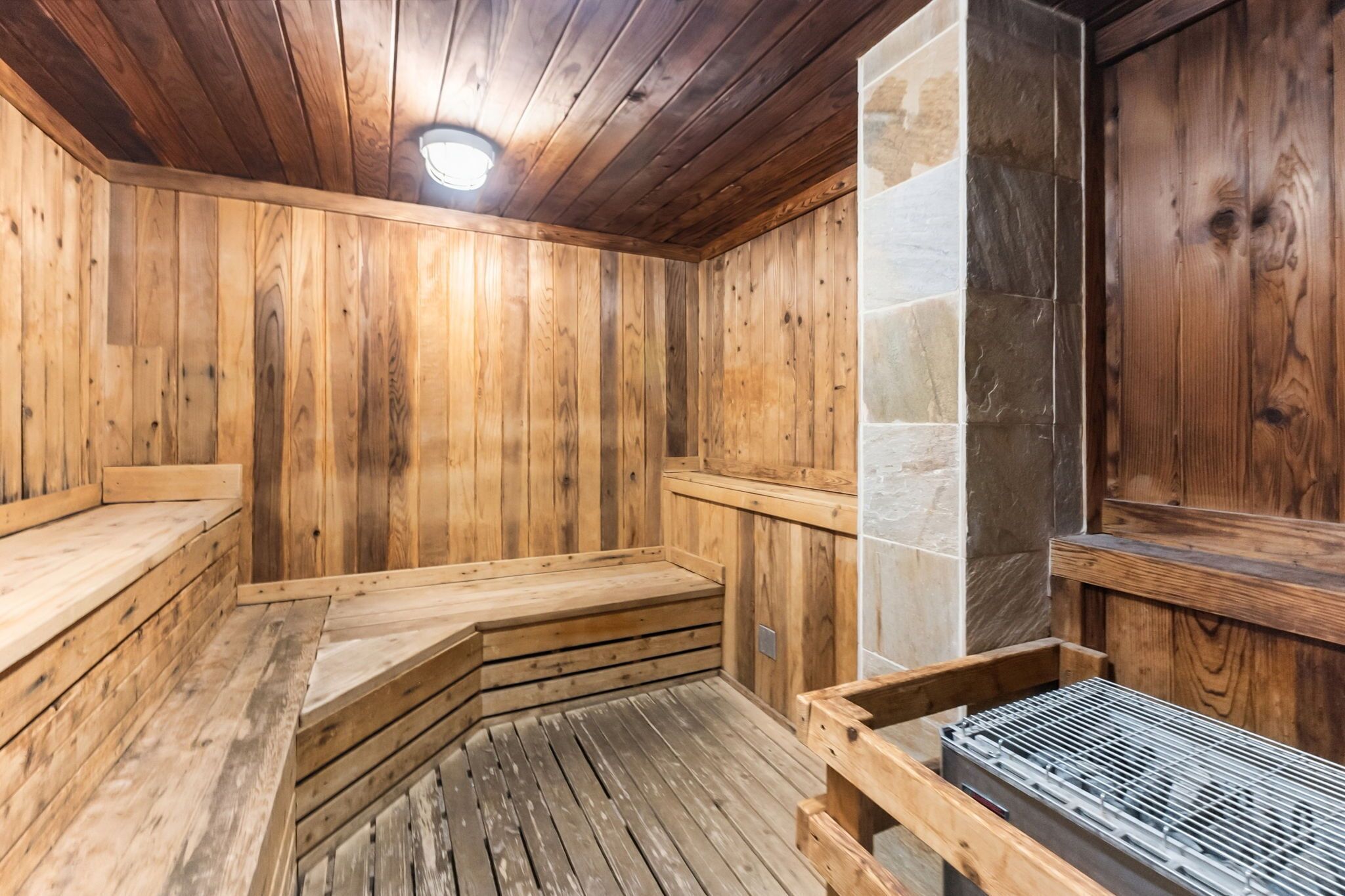 Un sauna en bois avec des bancs et un mur en pierre.