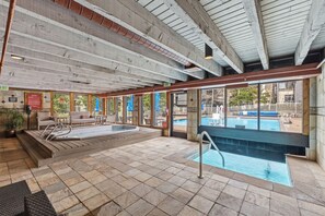 A pool area with a hot tub, lounge chairs, and a view of the pool. - Keystone Lakeside Condo | Outdoor Pool, Shuttle, and Mountain Access (Keystone)