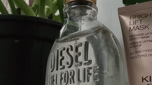 A bottle labeled 'DIESEL FUEL FOR LIFE 50 ML' and a tube of 'BRIGHT LIFT MASK' next to a potted plant. - Studio apartment in Prainha de Muquiçaba, 5 minutes from Praia do Morro, excellent for couples. (Guarapari)