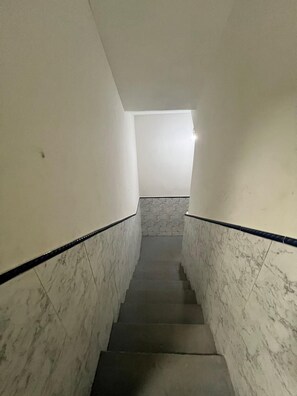 A narrow stairway with marble walls and black handrails, leading to a landing with a light fixture. - Studio apartment in Prainha de Muquiçaba, 5 minutes from Praia do Morro, excellent for couples. (Guarapari)